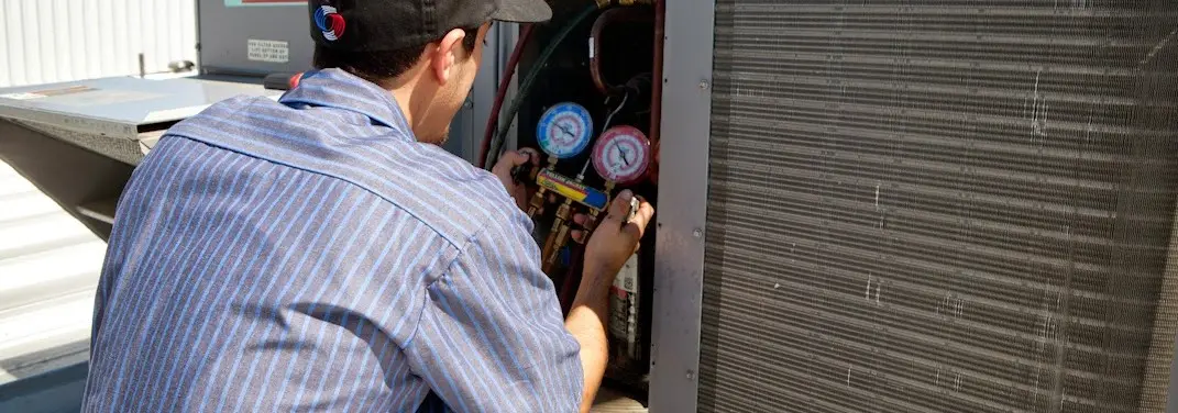 HVAC technician servicing a condenser unit in Calera